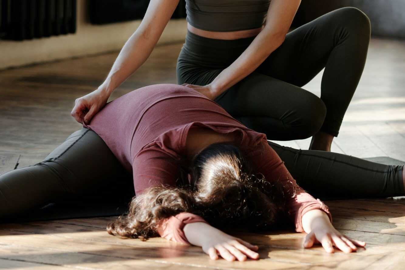 A pilates instructor helping with a stretching exercise
